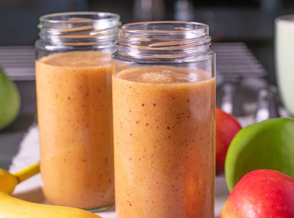 fresh and homemade blended fruit smoothie with a variation of fresh fruits served in glass jar on a kitchen table. Closeup and front view