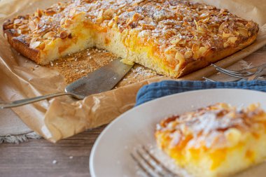 Badem ve meyveli çarşaflı kek. Taze pişmiş ve badem soslu ve mandalinalı ev yapımı kek. Kırsal masa arka planında balmumu kağıt üzerinde servis edilmiş. Çapraz bölüm görünümü