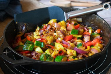 Tavada kızarmış sebze. Ev yapımı taze tava kızartılmış ya da karıştırılmış Akdeniz sebzeleri ahşap masa arkasında kırsal dökme demir tavada.