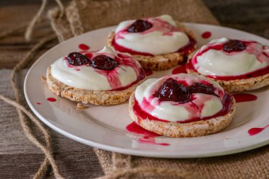 Lezzetli glütensiz kahvaltı ya da üzerinde kahverengi pirinç krakeri ve çok lezzetli Rus kirazlı reçeli olan rustik ve ahşap masa zemininde servis edilen Warenje adında bir tabakta. Yaklaş ve izole edilmiş görünüm