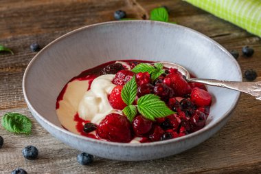 Çilekli yoğurt. Ev yapımı yoğurt ya da eritilmiş böğürtlenlerle yapılan ve ahududu yapraklı bir kasede servis edilen kuark yemeği. Yaklaş ve izole edilmiş görünüm