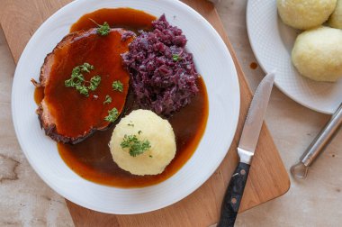 Kırmızı lahana, patates köftesi ve soslu nefis ev yapımı domuz rostosu. Geleneksel Alman yemeği.