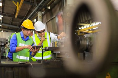 Fabrikanın içinde torna makinesi kullanan Asyalı mühendis ve tamirci.