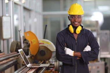 Afrikalı Amerikalı makine mühendisi portresi güvenlik ekipmanı ile fabrikada testere makinesinin yanında