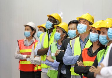 Müdür ve mühendislik ekibinin geri kalanı yeni normal ve sosyal mesafe politikası sırasında yüz maskesi takarak fabrikada yan yana duruyorlar.