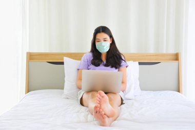 Sosyal uzaklık için yüz maskesi takan genç bir Asyalı kadın ve koronavirüs karantinası sırasında yeni bir normal. 