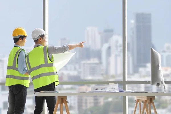 Dos Ingenieros Mirando Por Ventana Vista Del Paisaje Urbano Mientras — Foto de Stock