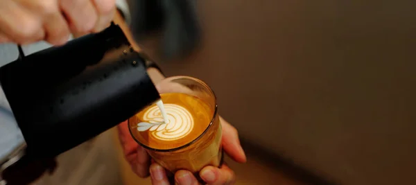 Barista sürahiyi, üzerinde lale desenli ve fotokopi alanı olan bir fincan kahveye köpüklü süt dökmek için kullanır.