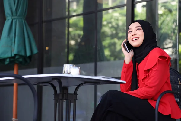 コピースペース付きで市内広場のカフェでコーヒーを飲みながら携帯電話を使用してヒジャーブを身に着けているイスラム教徒の女性 — ストック写真
