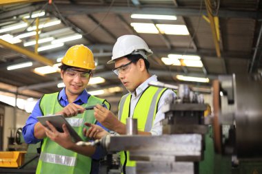 Fabrikanın içinde torna makinesi kullanan Asyalı mühendis ve tamirci.