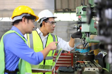 Fabrikanın içinde torna makinesi kullanan Asyalı mühendis ve tamirci.
