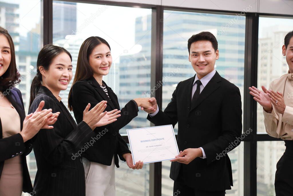 Group of Asian business corporation team celebrating together in the meeting room with CEO given certificate to the branch manager while the rest of employees are applauding