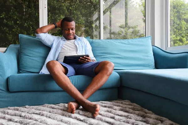 Hombre Afroamericano Usando Tableta Digital Mientras Está Sentado Sofá Acogedor —  Fotos de Stock