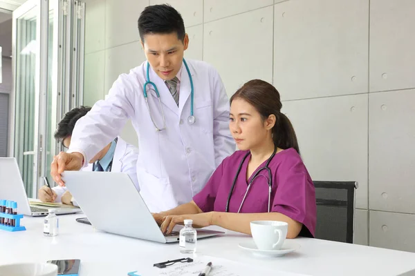 Senior doctor sharing advice in health care and patient examination during the medical meeting with other doctors using laptop computer