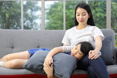 Asyalı kız kanepede annesinin kucağında uyuyordu.