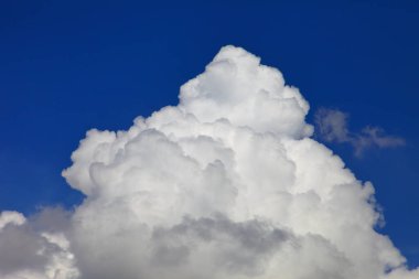 Parlak mavi gökyüzü, beyaz pofuduk, güzel kümülüs bulutu oluşumuyla güneşli bir günde tasarım arka planı ve duvar kağıdı için.