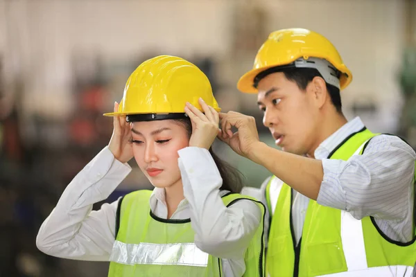 Industriarbetare Som Hjälper Varandra Att Bära Hatt När Arbetar Inne — Stockfoto