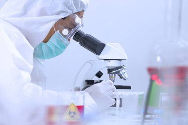 Tam koruma ekipmanları bilim araştırmacısı güvenlik laboratuvarında virüse karşı savaşmak için biyokimya alanında yeni aşılar üzerinde çalışıyor ve geliştiriyor.