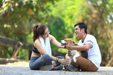 Asyalı çift parkta sabah egzersizi yaparken av köpekleriyle oynuyorlar.