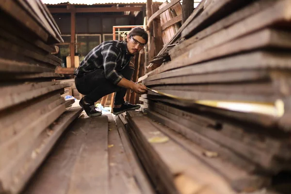 Genç Kafkasyalı marangoz kendi garajındaki tahta parçasını fotokopi alanı olan bir hobi için ölçüyor.