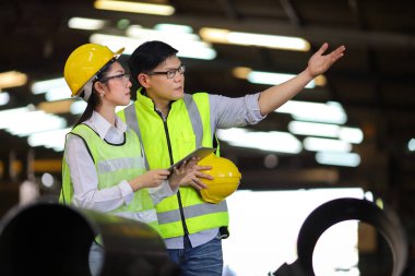 Mühendislerden oluşan tam güvenlik ekipmanları ağır sanayi fabrikasında çalışıyor ve teftiş ediyor.