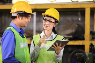 Tam teşekküllü güvenlik ekipmanları mühendis ekibi endüstriyel fabrikanın içindeki ağır makineleri inceliyor.