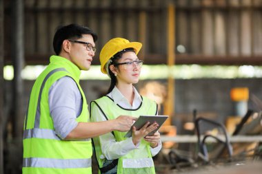 Tam güvenlik ekipmanlı mühendisler endüstriyel fabrikanın içinde çalışıyor ve teftiş ediyorlar.