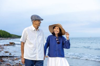 Asyalı yaşlı çift yaz tatillerinde sağlıklı bir ilişki ve emeklilik yıllarında mutlu bir evlilik hayatı için deniz sahilinde eğleniyor.