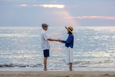 Asyalı yaşlı çift yaz tatillerinde deniz sahillerinde sağlıklı bir ilişki ve emeklilik yıllarında mutlu bir evlilik yaşamının tadını çıkarıyor.
