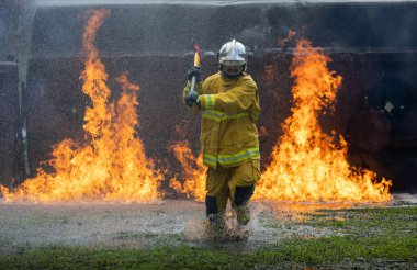Yangın geçirmez elbiseli itfaiyeci, yangın için yüksek alevlerle yanan binada barikatı yok etmek için balta tutuyor. Risk kurtarma görevi ve kaza yönetimi kullanımını söndürmek için.