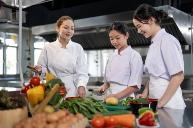 Profesyonel şef, genç aşçılık sınıfı öğrencisine, restoran mutfağında iyi yemek gurmesi ve aşçılık okulu için taze malzeme hazırlamasını öğretiyor.