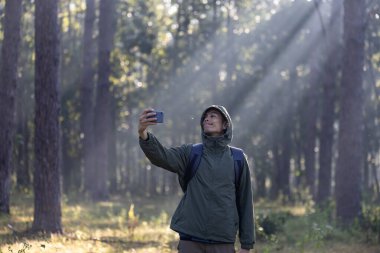 Asyalı yürüyüşçü, çam ormanlarında ender bulunan biyolojik çeşitliliği ve saha çalışmasındaki ekolojisti araştırmak ve keşfetmek için selfie çekerken yürüyüş yapıyor.