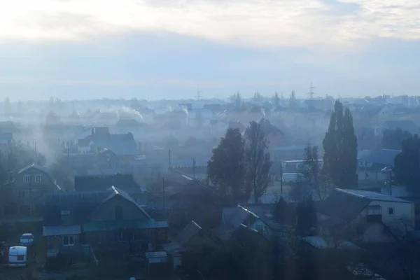 Gün doğumunda sabah sisi ve evlerin bacalarından duman.