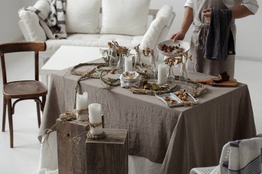 Process of decorating rustic style table with craft plates, linen tablecloth and napkins , gluten free pastry and wild berries