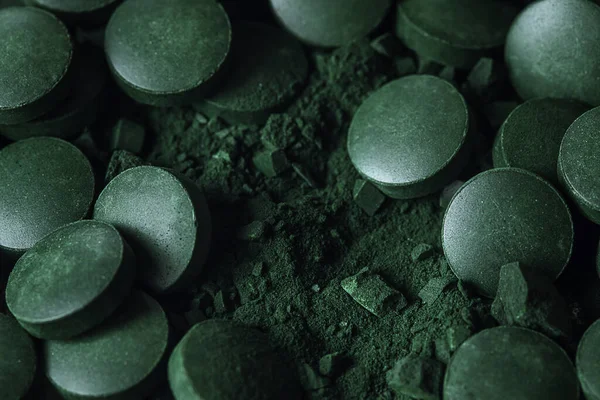 Spirulina powder and tablets algae. Macro close up.