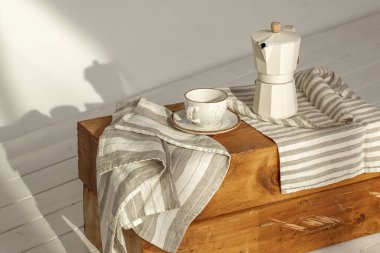 İtalyan kahve makinesi, ahşap saplı ve beyaz kahve fincanı, katı ahşap damgalı. Güneş ışığında kremalı havlularla süslenmiş. Duvarda güzel gölgeler yaratıyor.