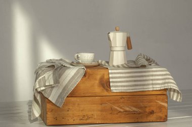 İtalyan kahve makinesi, ahşap saplı ve beyaz kahve fincanı, katı ahşap damgalı. Güneş ışığında kremalı havlularla süslenmiş. Duvarda güzel gölgeler yaratıyor.