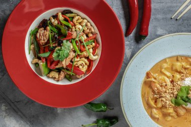 Kırmızı tabakta kaju fıstıklı lezzetli Tayland yemeği ve yukarıdan gri kil arka plan