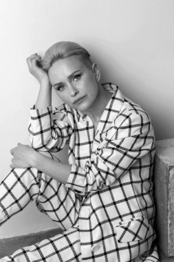 Zarif, karizmatik, sarışın ve kısa saçlı güzel geniş gülüşlü, büyük beden keten takım elbiseli, stüdyoda soyutlanmış poz veren kadınlar. Siyah ve beyaz versio