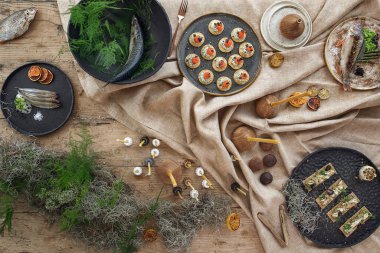 El yapımı el yapımı el yapımı tabakları ve keten masa örtüsü üzerinde çiğ balıklar ve toprak tonlarında ahşap aksesuarlar.