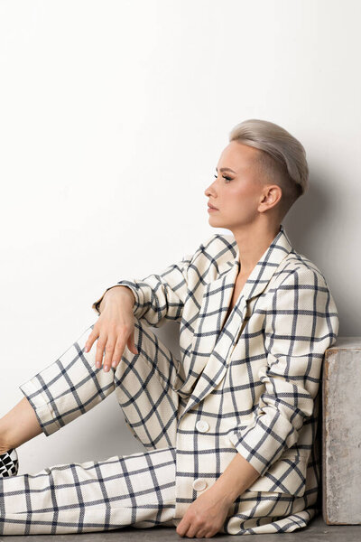 Elegant ant charismatic short blond haired with natural makeup businesswomen wearing oversized linen suit with blue stripes posing isolated in studi