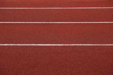 Stadyum kauçuk arka planında paralel beyaz çizgileri olan kırmızı yarış pisti