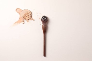 Çarpışan bej yüzler, sıvı toz ve sıfır atık ahşap barut fırçası. Bej arkaplanda makro makyaj dokusu