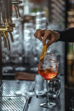 Barmen büyük şarap kadehinde aperol spreyi kokteyli yapıyor.