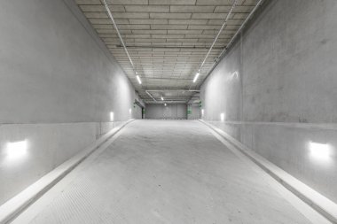 Empty public underground parking lot or garage interior with concrete stripe painted columns and signs