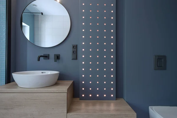 Interior photography of modern minimalist bathroom with navy blue walls and wood furniture