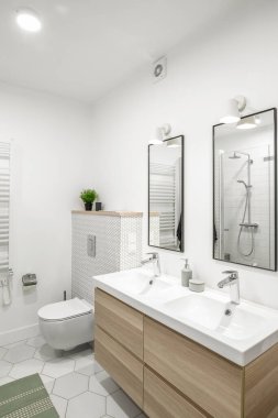 Modern minimalist banyo iç tasarımı beyaz fayanslar, iki beyaz lavabo ve doğal ahşap mobilyalar.