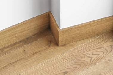 Oda köşesi, iki farklı doku: beyaz duvar ve doğal meşe ağacı zemin.