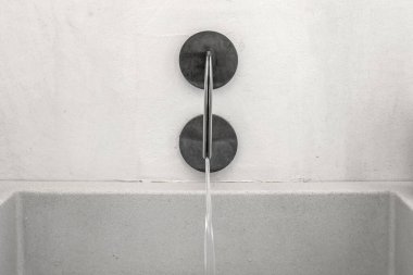 Çağdaş ve şık modern metal su musluğu, akan su ve taş lavabosu var.