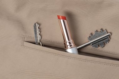 Fransız trençkotunun cebinde kırmızı ruj ve anahtarlar var.